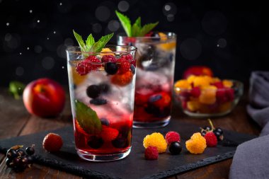 Siyah arka planda şeffaf bir bardakta çilekli limonata..