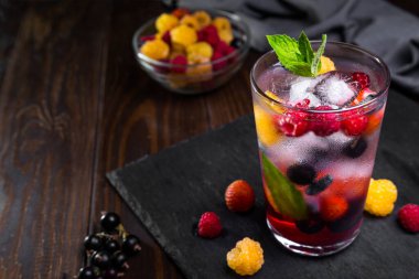 Siyah arka planda şeffaf bir bardakta çilekli limonata..