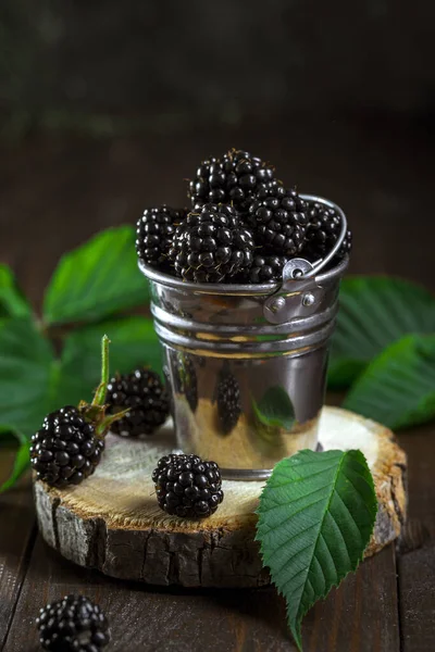 Koyu ahşap arka planda kovadaki böğürtlenler.