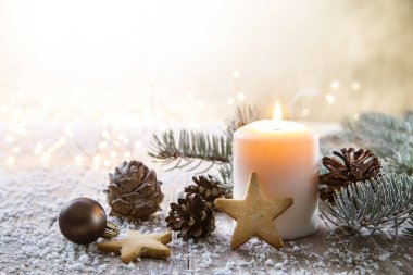 Kırsal ahşap tahtalarda beyaz Noel mumu - Doğal elementler, dallar, çam kozalakları ve kurabiyelerle süsleme.