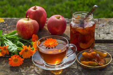 Ahşap bir masada elma reçeli ve takviyeli çay..
