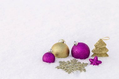 Bir açıklıkta, karda yatan Noel süsleri..