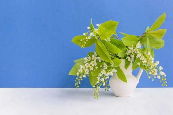 Spring white flowers in a vase on a blue background