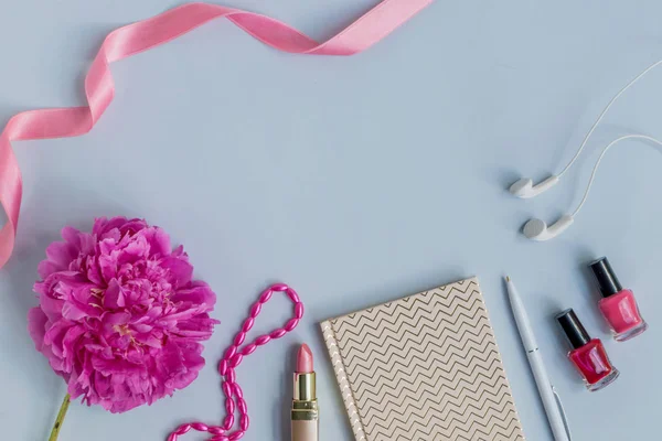Flat lay desk with pink peony, cosmetics and accessories