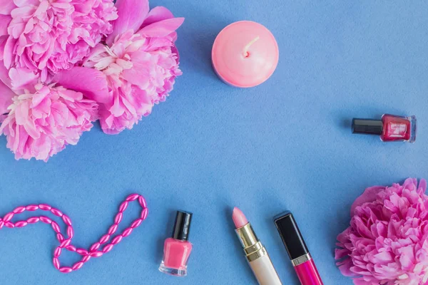 Flat lay desk with pink peonies and cosmetic