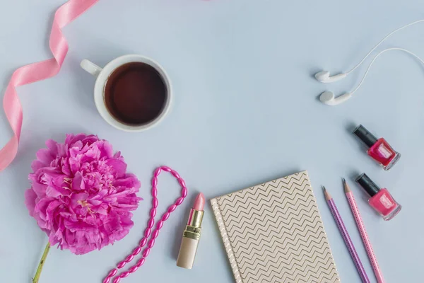 Flat lay desk with pink peony, cosmetics and accessories