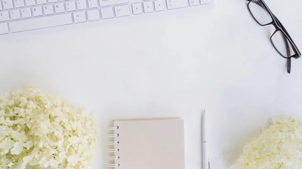 Blogger or freelancer workspace with notebook and white flower h