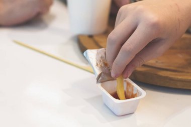 Kafede fast food yiyen çocuk. Gıda kavramı ve sağlıksız yaşam tarzı. Sepette patates kızartması ve ketçap ve soslu büyük hamburger