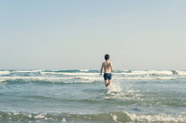 Sevimli genç çocuk sahilde eğleniyor