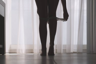 Seksi bacaklar perdelerin arka planında bir odada onu beyaz külot çıkararak güzel kadının siluet alt görünümü