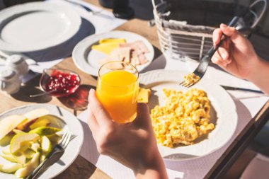 Kadın çırpılmış yumurta, taze portakal suyu, peynir, ekmek ve reçel ile kahvaltı yapar..   