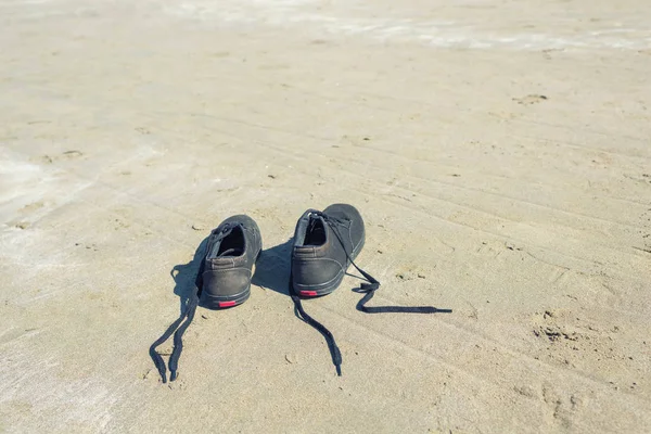Deniz Arka Planda Kumlu Plajda Siyah Spor Ayakkabıları Yaz Seyahat — Stok fotoğraf