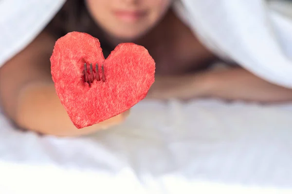 Beautiful girl in bed gives heart from watermelon on a fork. Concept