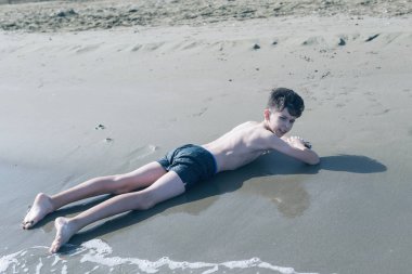 Sevimli genç çocuk sahilde eğleniyor