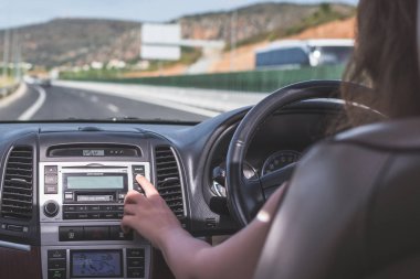 Kız Kıbrıs'ta otoyolda sürüyor. Arabanın arka koltuğundan ön cam, yol ve sürücü görünümü