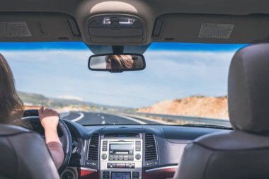 Kız İspanya'da otobanda araba kullanıyor. Arabanın arka koltuğundan ön cam, yol ve sürücü görünümü