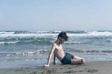 Sevimli genç çocuk sahilde eğleniyor