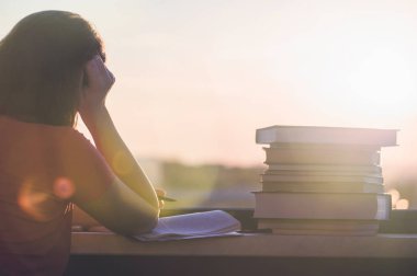 Gün batımı kasaba arka plan üzerinde üniversite sınavı için hazırlık kitapları bir sürü kız öğrenci. Eğitim kavramı