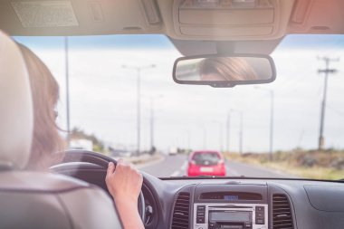 Kız Portekiz'de otobanda sürüyor. Arabanın arka koltuğundan ön cam, yol ve sürücü görünümü