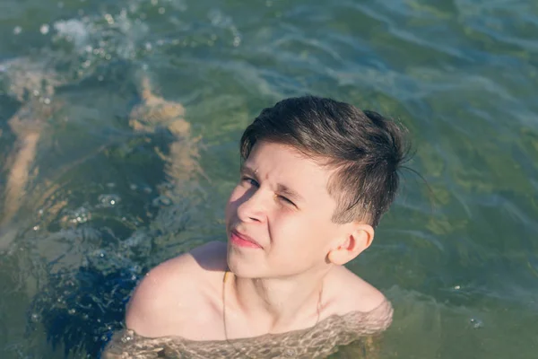 13 years old boy swimming and relaxation in the sea waves. Concept of family summer vacation