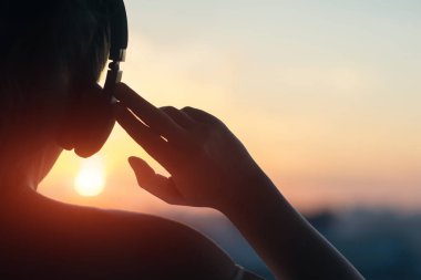 Günbatımında şehir içinde müzik dinlemek kulaklık kız 