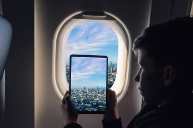 Beyaz çocuk uçak penceresinden San Francisco cityscape üzerinden fotoğraf çekmek tablet pc kullanarak. California. Abd