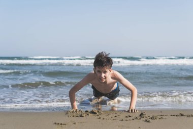 çocuk deniz arka plan üzerinde sahilde kumüzerinde dışarı wred. Spor ve sağlıklı yaşam tarzı kavramı