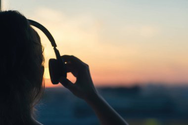 Günbatımında şehir içinde müzik dinlemek kulaklık kız 