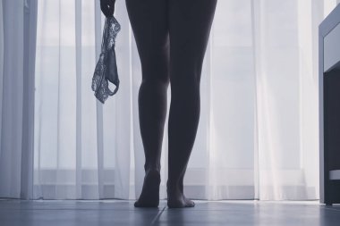 Seksi bacaklar perdelerin arka planında bir odada onu beyaz külot çıkararak güzel kadının siluet alt görünümü