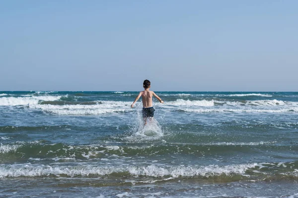 Teen boy swimming in the wave of sea in the tropical resorts. Concept of summer vacation