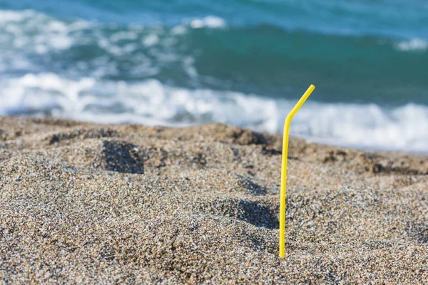 Plastic colored straw  for drinking in the sand on the beach. Concept