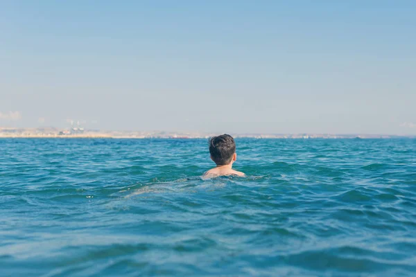 13 years old boy swimming and relaxation in the sea waves. Concept of family summer vacation