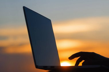 günün sonunda gün batımında bir kadın el ve dizüstü siluet. Kavram 