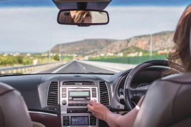 Genç bir kadın İtalya 'da otoyolda sürüyor ve cep telefonunda GPS navigasyon uygulaması kullanıyor. Arabanın arka koltuğundan bak.