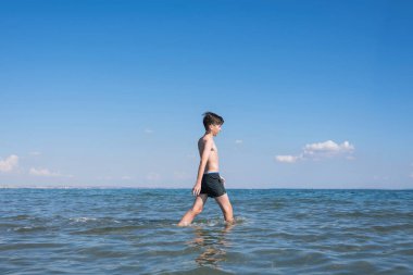Su sıçraması ile çocuk ve deniz dalgaları. Yaz tatili konsepti 