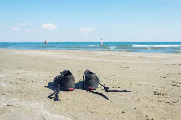 Zwarte Sneakers Het Zandstrand Achtergrond Van Zee Zomer Reis Concept — Stockfoto