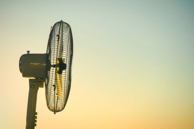 Açık bir günbatımı gökyüzü nün arka planına karşı elektrikli fan vantilatör. Kavram