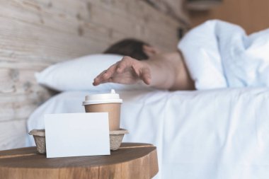 Uyuyan bir kız için bir sürpriz olarak yatak odasında masada duran metin için boş etiket ile kahve bir kağıt fincan. 