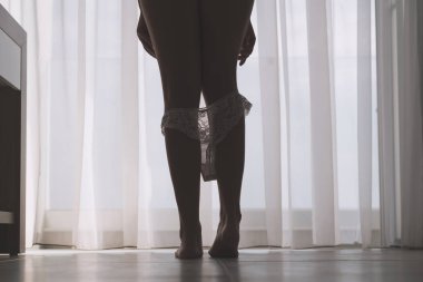 Seksi bacaklar perdelerin arka planında bir odada onu beyaz külot çıkararak güzel kadının siluet alt görünümü