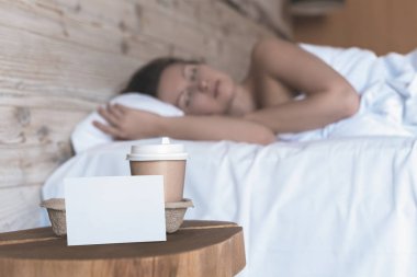 Uyuyan bir kız için bir sürpriz olarak yatak odasında masada duran metin için boş etiket ile kahve bir kağıt fincan. 