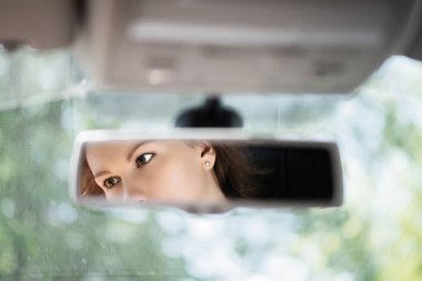 Arabanın dikiz aynasında güzel bir genç kadın yüz yansıması. Kavram