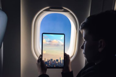 Beyaz çocuk gökdelenler ile uçak penceresinden New York'ta fotoğraf çekmek tablet pc kullanarak. Abd