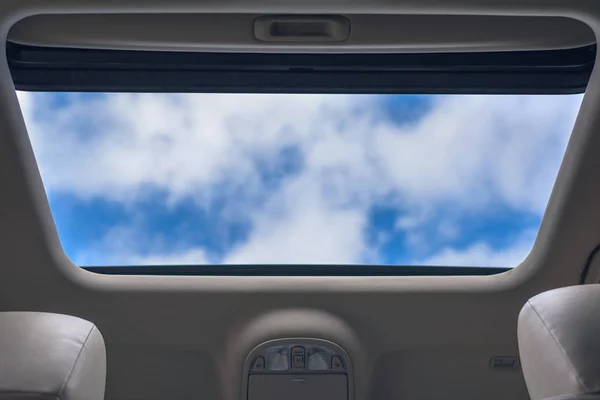 View of the cloudy sky through the open hatch of the car