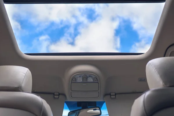 View of the cloudy sky through the open hatch of the car