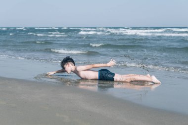 Sevimli genç çocuk sahilde eğleniyor