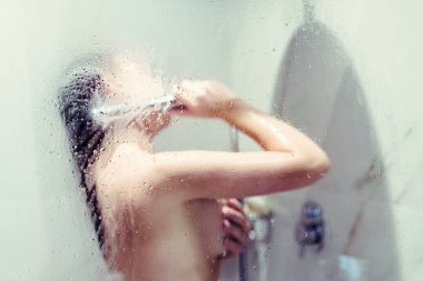 Çıplak güzel kadın ıslak sisli cam arkasında bir duş alarak.