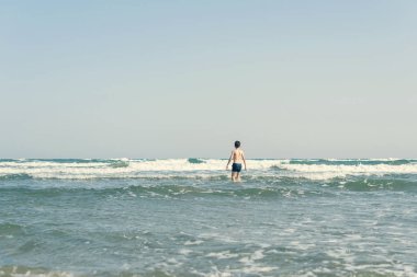 Sevimli genç çocuk sahilde eğleniyor