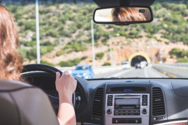 Kız Tenerife, Kanarya Adaları'nda yolda gidiyor. Arabanın arka koltuğundan ön cam, yol ve sürücü görünümü