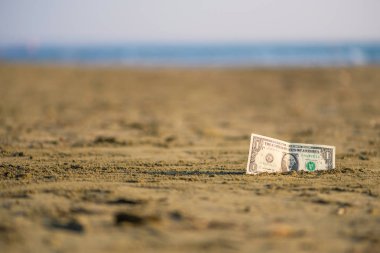 Sahildekumda bir dolar değerinde banknot. Ucuz seyahat ve tatil kavramı. Promosyon ve indirim