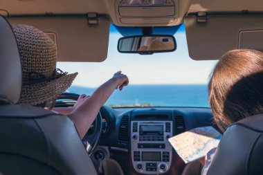 Araba sürerken yön arayan iki kadın.